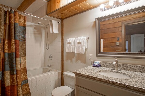Ein Badezimmer mit Dusche, Toilette, Waschbecken und Spiegel.