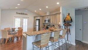 Een moderne keuken met een centraal eiland, inbouwapparatuur en rieten stoelen.