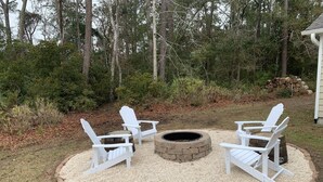 Een ronde zithoek met vier Adirondack-stoelen rond een vuurkorf.