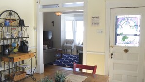 A dining area with a wooden table, benches, and a ceiling fan. There is a door with a glass window and a sign on the wall. - Enjoy some R & R at this historic cottage in the best neighborhood in town! (Silverton)