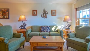 Una sala de estar acogedora con sofás verdes, una mesa de centro de madera y lámparas decorativas.