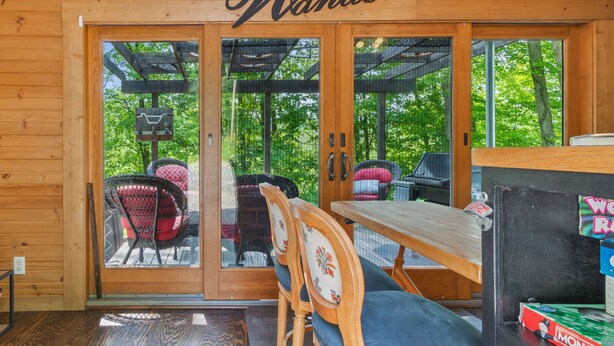 En træhytte med et 'Wander' skilt, en skydedør, der fører ud til en udendørs terrasse med stole og et bord.