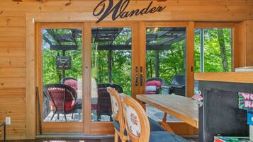Step into the cozy cabin, featuring a wooden table and chairs with floral upholstery, and enjoy the expansive deck with outdoor seating.