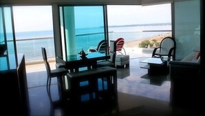 Un soggiorno moderno con un'ampia vetrata che si apre su un balcone vista mare.