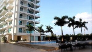 Un hotel moderno con area piscina, palme e posti a sedere all'aperto.