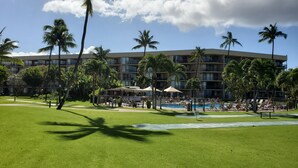 Een hotel met een zwembad, palmbomen en een verzorgd gazon.