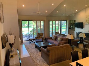 A spacious living room with a sofa, coffee table, and chairs, a fireplace, and large sliding glass doors leading to a patio. - PALM VALLEY COUNTRY CLUB🌴UPDATED 2BED+DEN🛋️ 48POOLS💦 WINTER/SPRING OPEN!BOOK NOW! (Palm Desert)