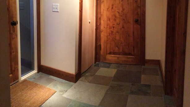 A hallway with a wooden door, a coat rack, and a tiled floor. - Bright, Modern Loft. 5 Miles to Ski Resort, National Park, or Downtown Jackson (Wilson)