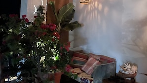 A cozy outdoor seating area with a cushioned bench, a potted plant, and a hanging light fixture. - Zona Romantica Area with Beautiful Bay View and Large Terrace (Puerto Vallarta)