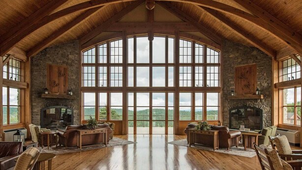 Una habitación amplia con techo alto y ventanas grandes, que cuenta con chimenea, zona de estar y vistas al exterior.