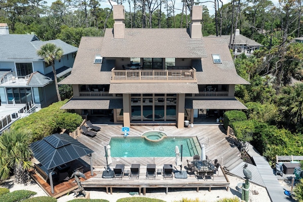 A large two-story house with a swimming pool, outdoor seating, and a covered patio area.