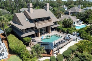 A multi-story house with a large deck, a swimming pool, and a covered outdoor area.