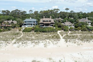 Una propiedad frente a la playa con varias casas, una playa de arena y árboles densos al fondo.