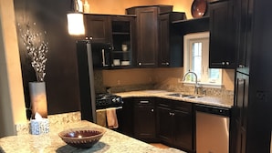 A modern kitchen with dark cabinetry, granite countertops, and stainless steel appliances. - Great location, beautiful mountain and sunset views, hot tub and shuffleboard. (Fairview)