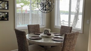 A dining area with a round table, four wicker chairs, and a hanging light fixture. - All Sports Lake / Golf, minutes from many players (Lapeer)