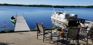 Relax by the serene lake with a dock, canoe, and outdoor seating area.