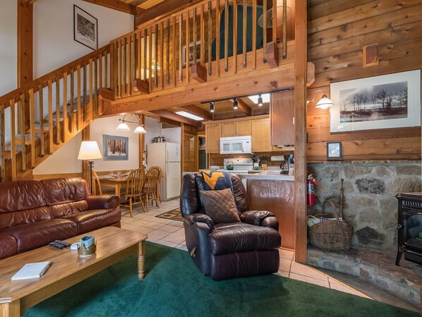 A cozy cabin interior with a wooden staircase, leather sofas, a dining area, and a kitchen. - Powder Monkey #3: 3 Bedrooms, 2 Full Baths: Slope Side. (Snowshoe)