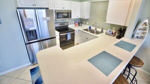 Una cocina moderna con armarios blancos, electrodomésticos de acero inoxidable y una isla central.