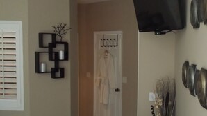 Un pasillo con perchero, televisor montado en la pared y una puerta con abrigo colgado.