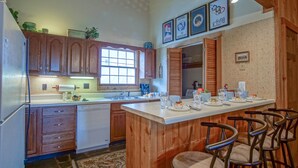 A kitchen with wooden cabinets, a built-in island with bar stools, and various kitchen appliances. - Whistlepunk #24: 4 Bedroom, 3 Bath:  Slope Side, Wood Fireplace. (Snowshoe)
