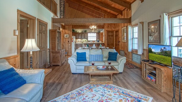 A spacious living area with a high ceiling, wooden beams, a sofa, a coffee table, and a television. - Whistlepunk #24: 4 Bedroom, 3 Bath:  Slope Side, Wood Fireplace. (Snowshoe)