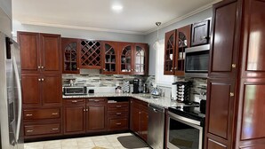 A kitchen with dark wooden cabinets, stainless steel appliances, and a tiled floor with diamond patterns. - Urban Edition (Long Pond)