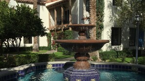 A swimming pool with a central fountain, surrounded by a tiled border and decorative elements.