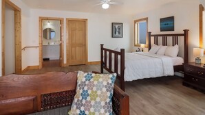 Een slaapkamer met een houten bed, een nachtkastje, een stoel en een plafondventilator.
