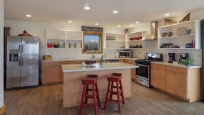 Een moderne keuken met een centraal eiland, houten kasten en inbouwplanken.