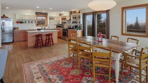 Een moderne keuken met een centraal eiland, een houten eettafel en barstoelen.