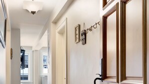 A hallway with wooden flooring, a door with a black handle, and a light fixture on the ceiling. - Stadium District Room With A View (Tacoma)
