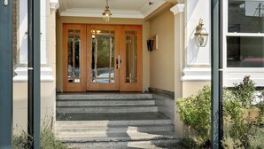 A building entrance with a covered porch, double doors, and steps leading to a driveway. - Stadium District Room With A View (Tacoma)