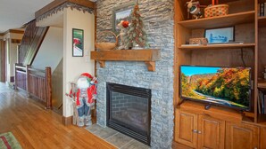 Ein Wohnzimmer mit Kamin aus Stein, Holzregalen und einem Fernseher.