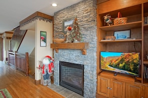 Una sala de estar con chimenea de piedra, estanterías de madera y un televisor.