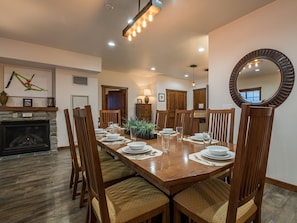 Un comedor con una gran mesa de madera dispuesta para seis personas, rodeada de sillas de madera con asientos acolchados.