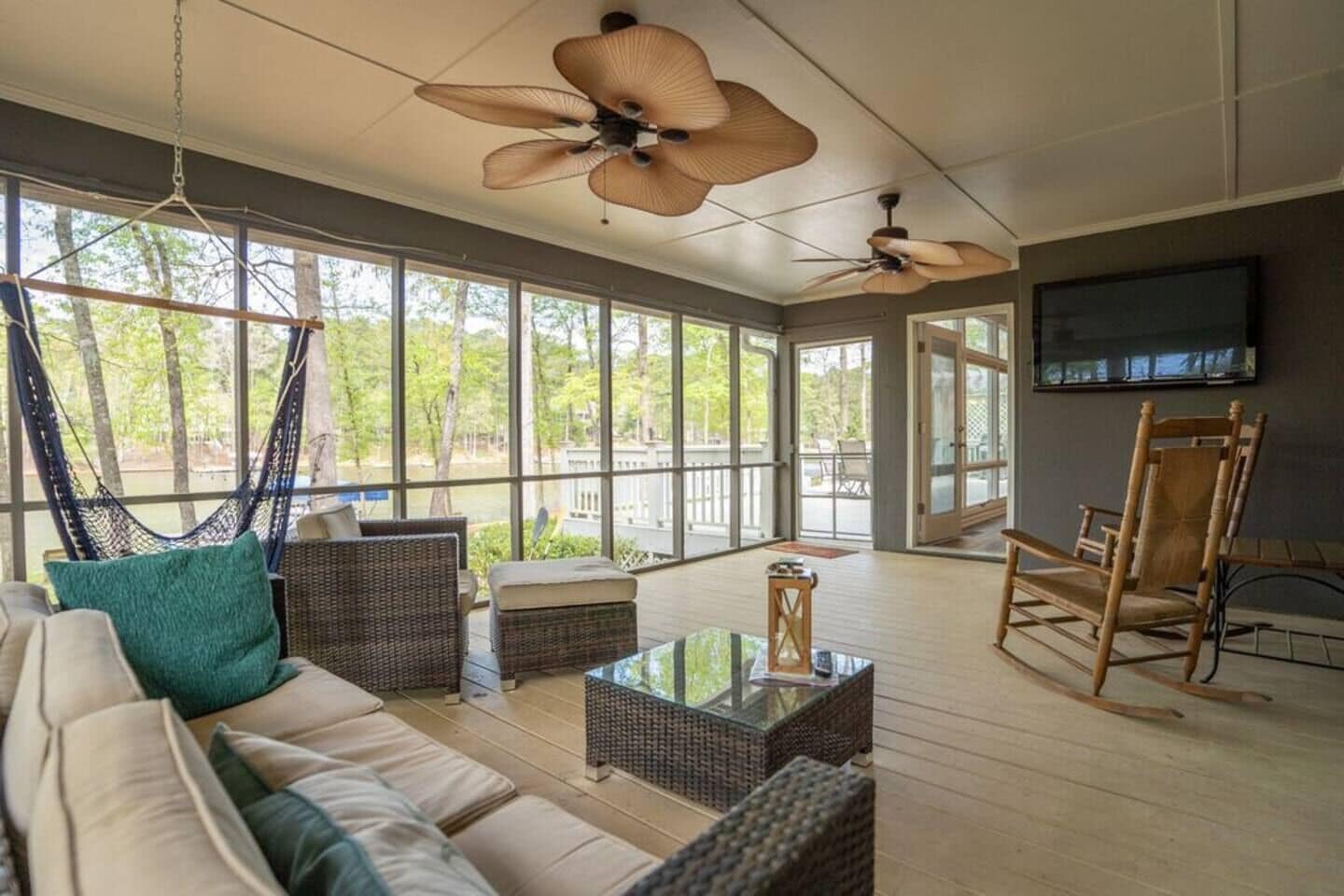 Screened in porch with TV, outdoor couch and rocking chairs