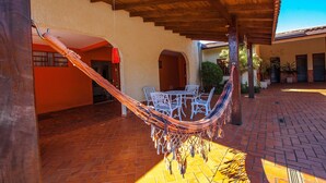 A covered patio with a hammock, outdoor furniture, and a brick floor. - Foz Temporada (Foz do Iguaçu)