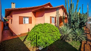 A house with a tiled roof, a chimney, and a small garden with a potted plant and cacti. - Foz Temporada (Foz do Iguaçu)