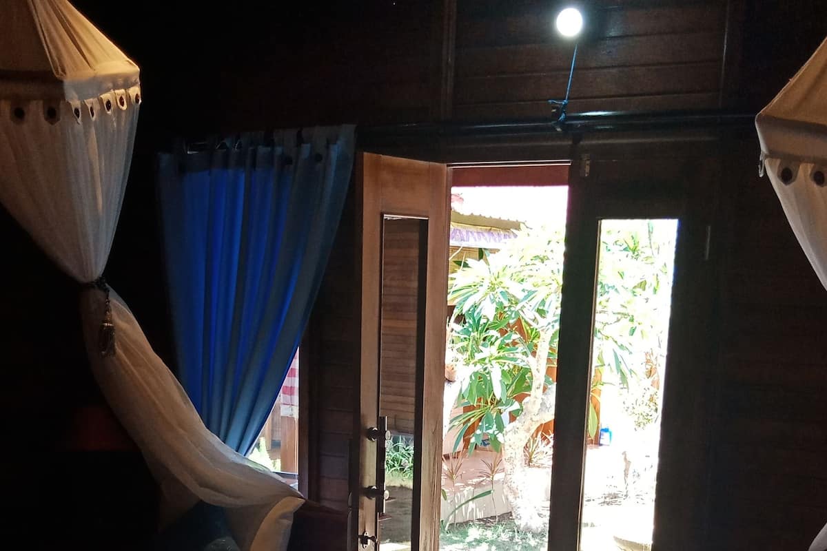 Una habitación con dos camas, techo de madera y una puerta que da al exterior.