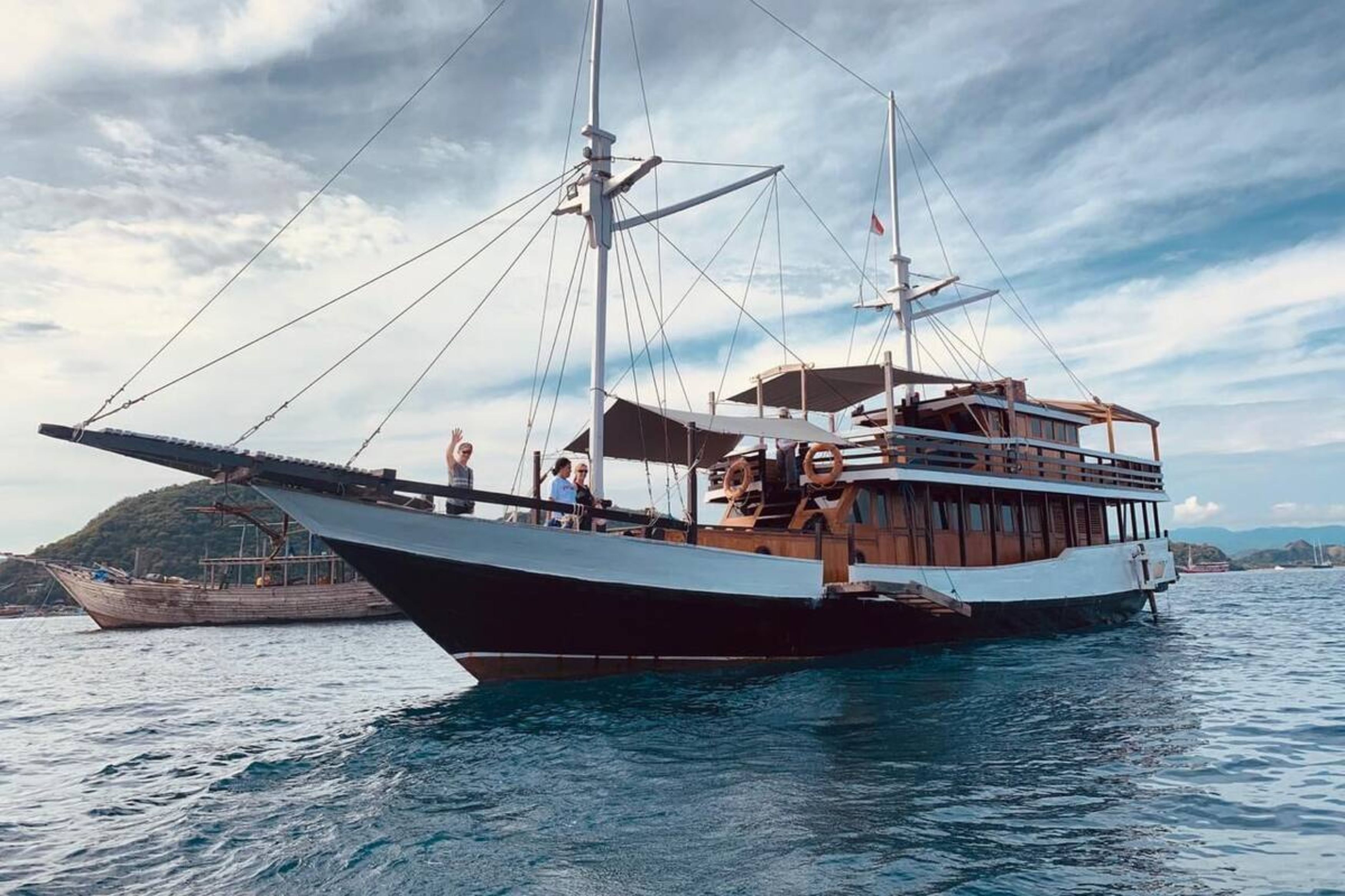 A large, traditional sailing boat with multiple decks and passengers on board.
