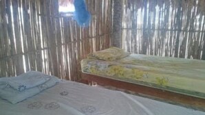 A room with two beds, one with a floral bedspread and the other with a plain one. - Tripsyala (Ailigandí)