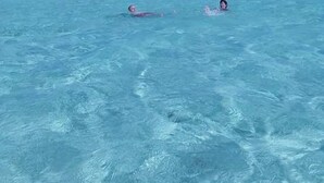 A clear blue sea with two people swimming. - Tripsyala (Ailigandí)