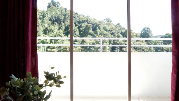 A room with a large window overlooking a lush green landscape and a bridge. - PLAY Residence at Cameron Jaya (Tanah Rata)