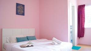 A neatly made bed with white bedding, a blue pillow, and a rolled towel. There is a small plant on the bed, and a book is open on the left side. - PLAY Residence at Cameron Jaya (Tanah Rata)