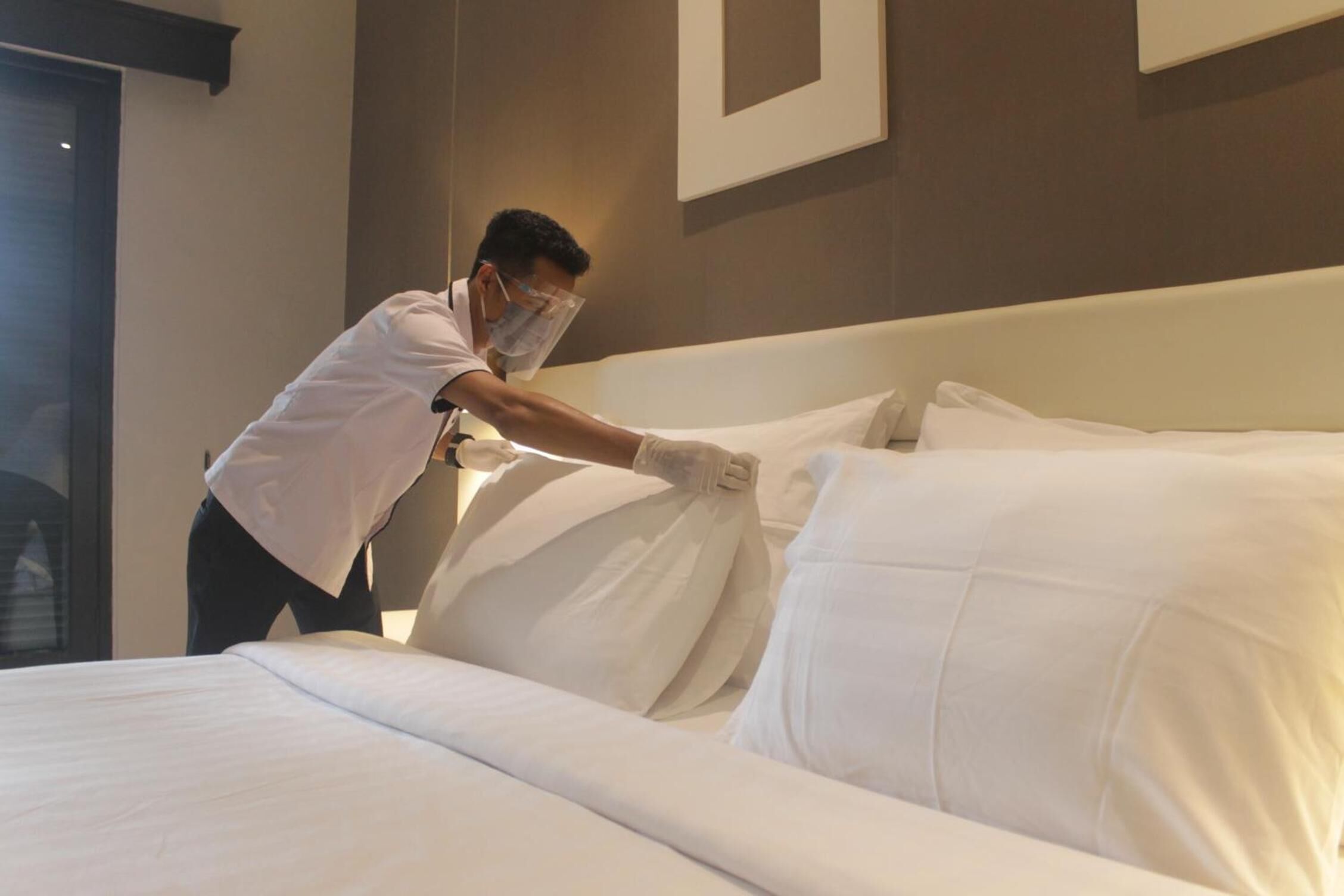 Una habitación de hotel con una cama bien hecha, un cabecero y un cuadro en la pared.