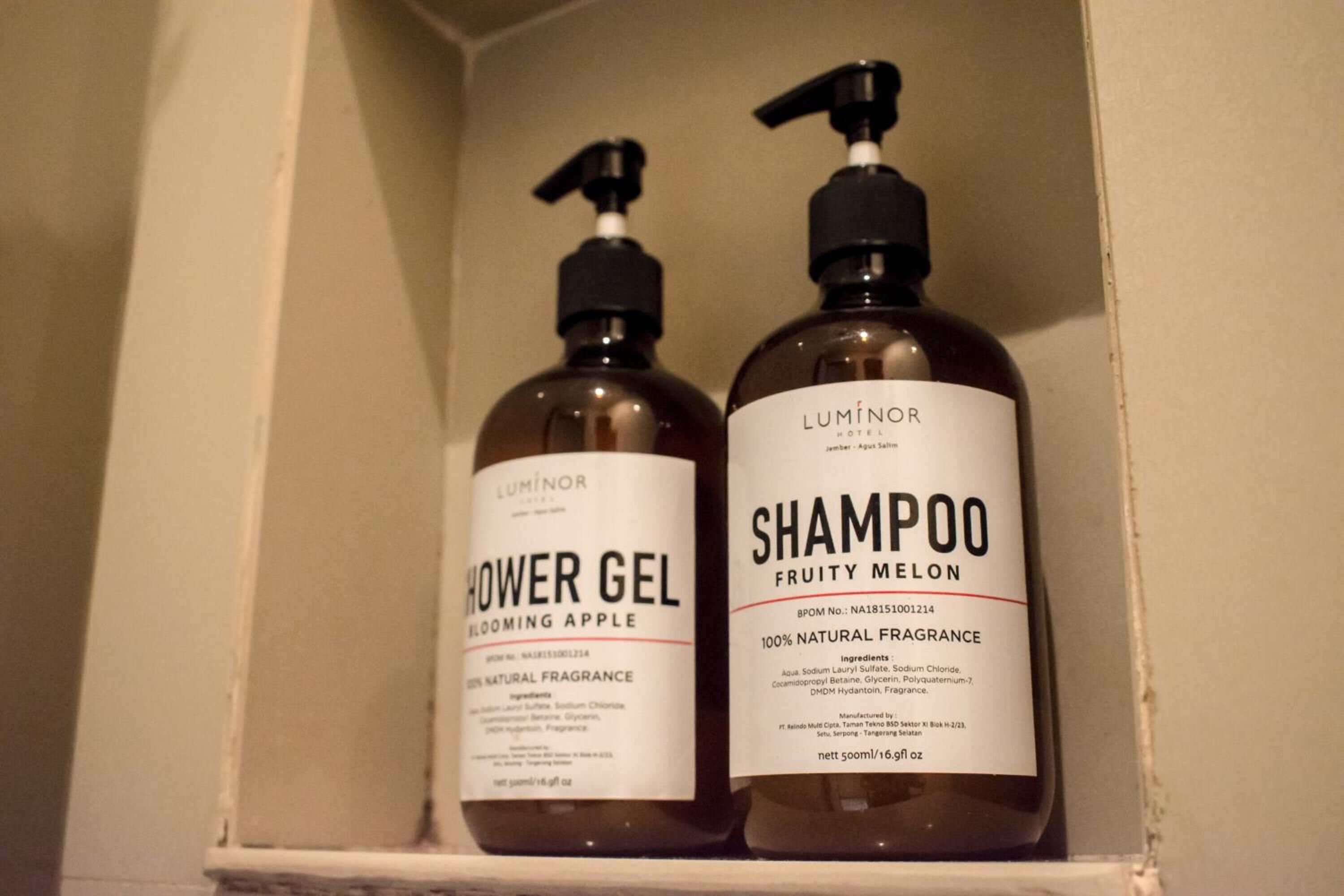 Zwei Flaschen Luminar Hotel Duschgel und Shampoo auf einer Ablagefläche.