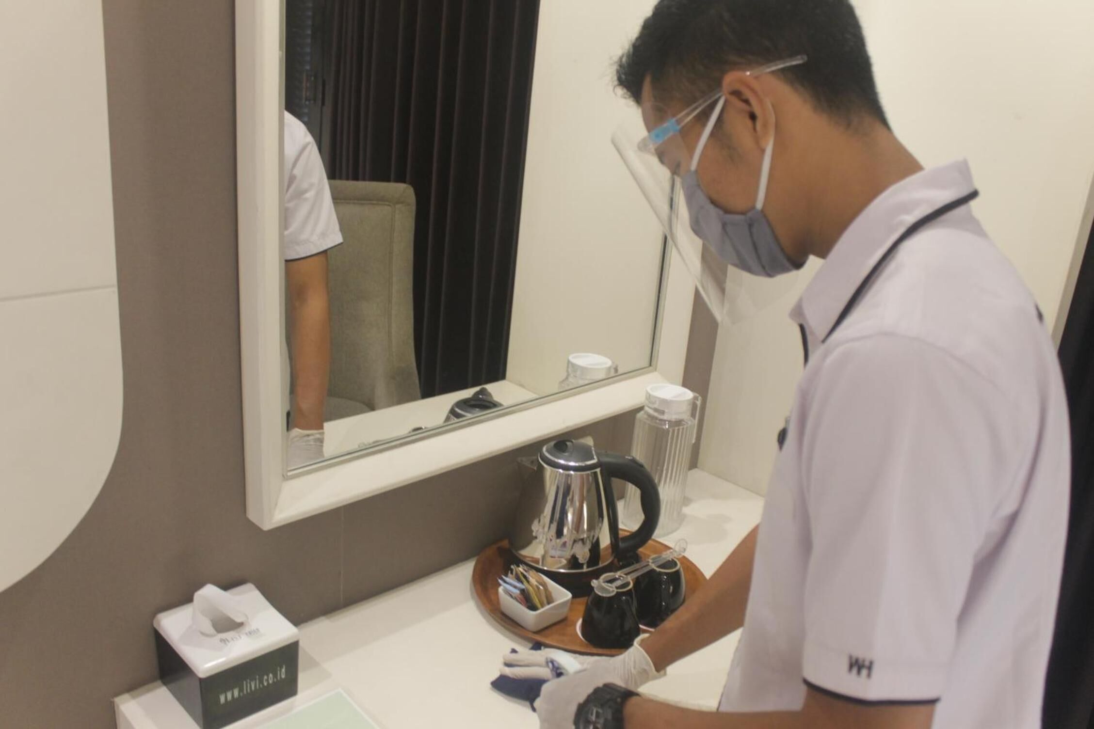 A hotel room with a large mirror, a coffee maker, and a tissue box on the counter.