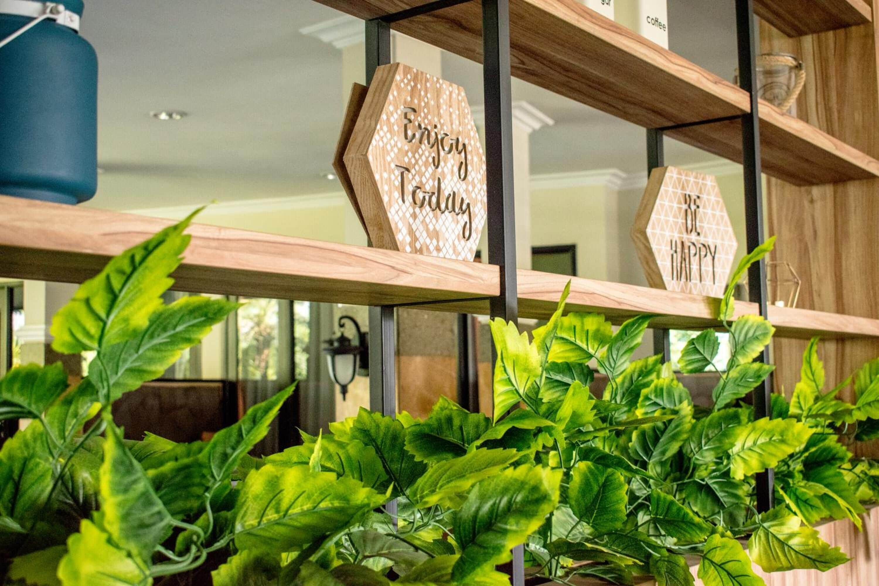 A wooden shelf with hexagonal signs saying "Enjoy Today" and "Be Happy".