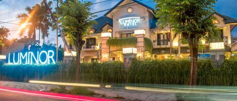 A hotel named Luminor with a modern architectural design, featuring balconies and a well-lit facade.