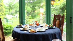 Mesa de comedor lista para el almuerzo, con vistas a un jardín a través de amplias ventanas.
